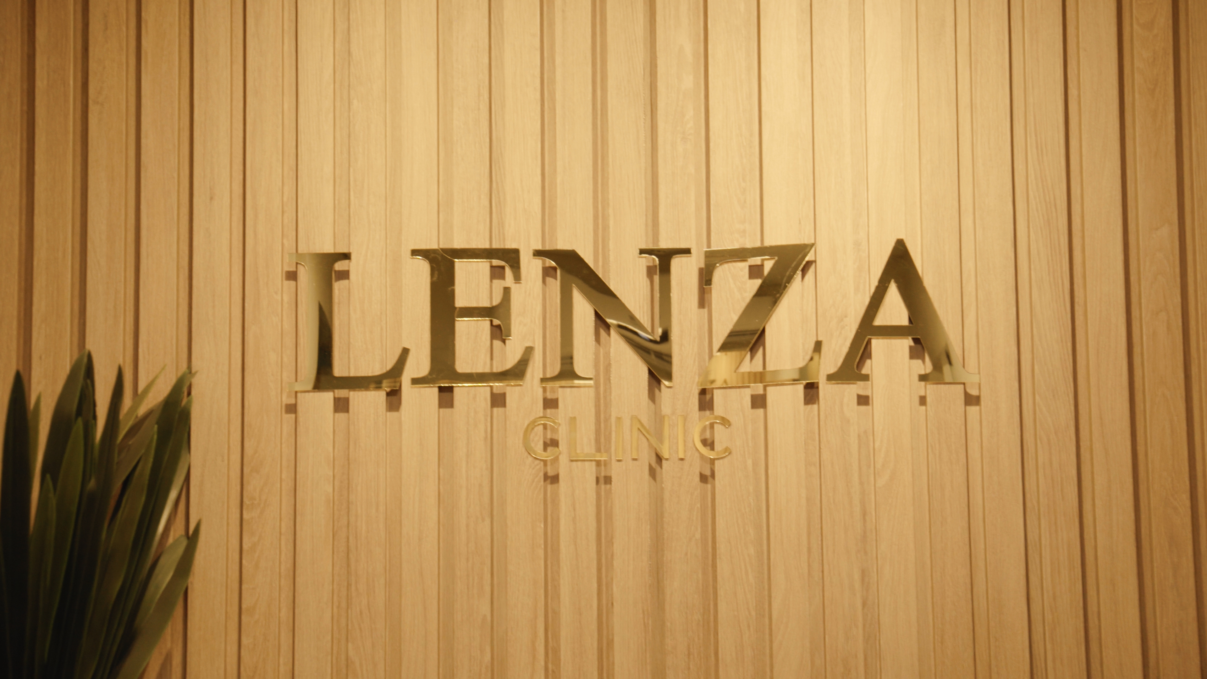 Logo Lenza dourado sobre parede de madeira